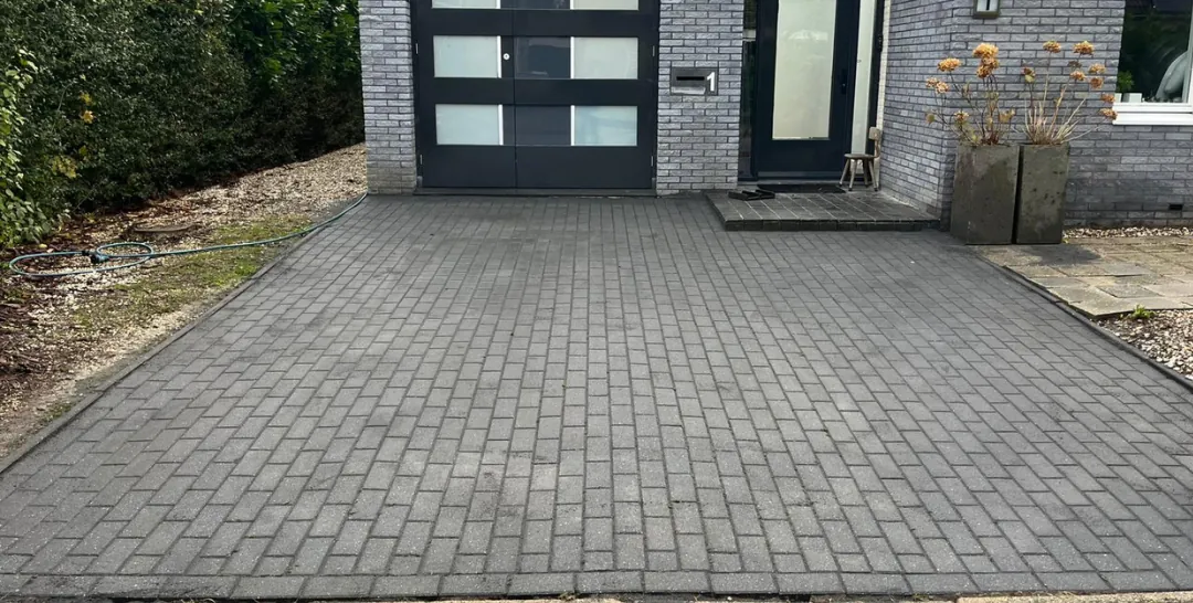Een schone oprit van antracietkleurige klinkers voor een huis in Groningen, na onze reiniging