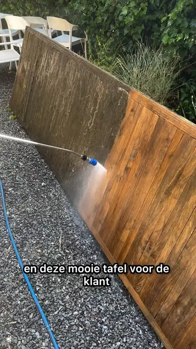 Een houten schutting wordt half schoongespoten: links vies, rechts schoon